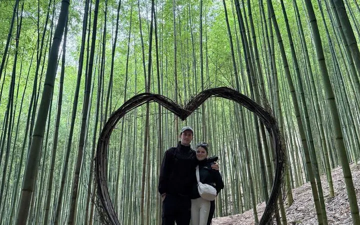 Couple standing in bamboo forest with heart-shaped frame, Mu Cang Chai motorbike tour.