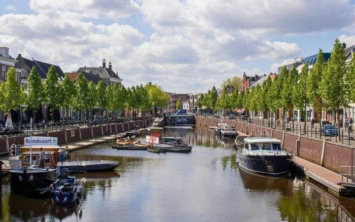 Canal view with boats and tree-lined streets in Breda, Netherlands, featured in a self-guided audio tour.