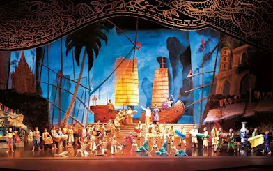 Performers on stage at Siam Niramit Phuket, depicting historical scenes with traditional costumes and ships.