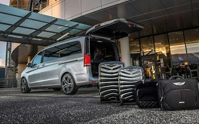 Van with open trunk and luggage at Hurghada hotel entrance for airport transfer.