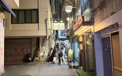 Seoul alleyway with people gathering outside a lit restaurant, part of Chimaek night food tour.