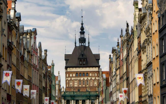 Gdansk Old Town street view with historic architecture and flags, featured in self-guided audio tour.