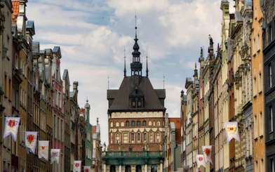 Gdansk Old Town street view with historic architecture and flags, featured in self-guided audio tour.