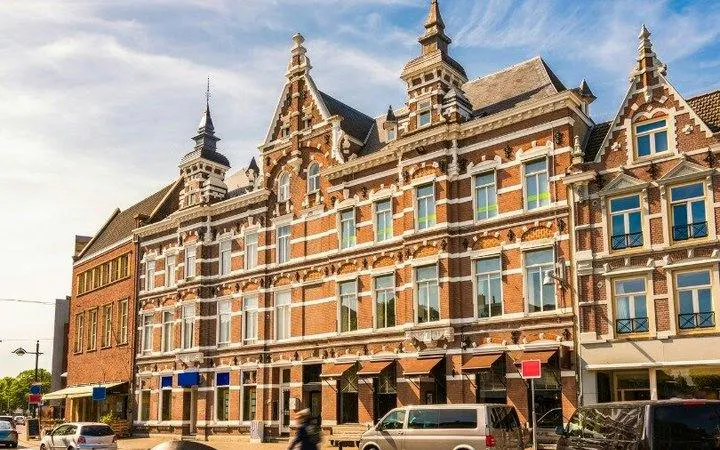 Historic building with ornate gables on a street in Breda, Netherlands, part of a self-guided audio tour.