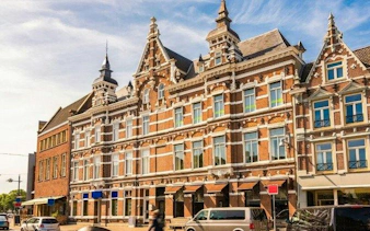 Historic building with ornate gables on a street in Breda, Netherlands, part of a self-guided audio tour.
