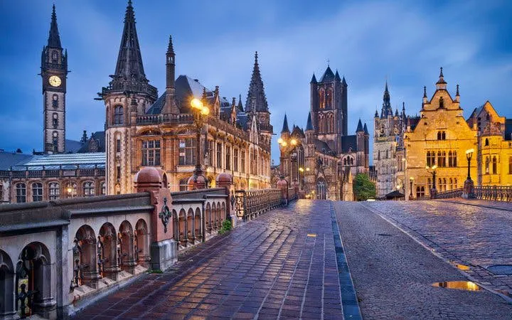 Ghent cityscape with historic buildings and St. Nicholas' Church at dusk, Belgium.