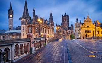 Ghent cityscape with historic buildings and St. Nicholas' Church at dusk, Belgium.