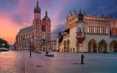 Krakow Main Square with St. Mary's Basilica and Cloth Hall at sunset.