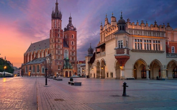 Krakow Main Square with St. Mary's Basilica and Cloth Hall at sunset.