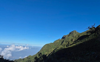 Mountain view along Sapa trail with clear blue sky and distant clouds.