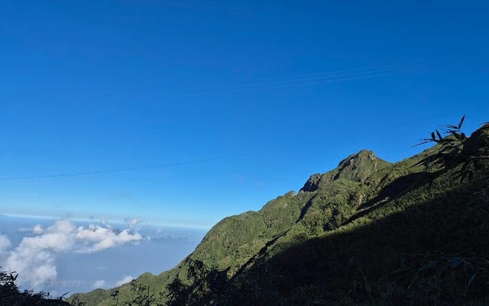 Mountain view along Sapa trail with clear blue sky and distant clouds.