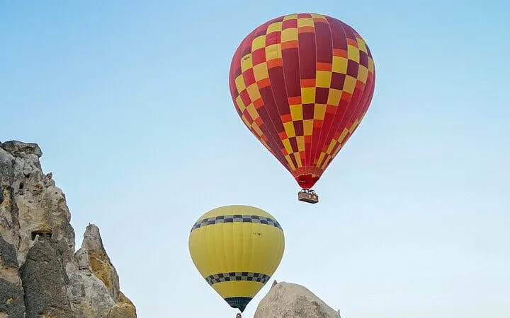 Hot air balloons floating over Cappadocia rock formations at sunrise.