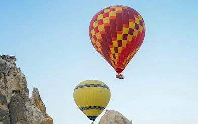 Hot air balloons floating over Cappadocia rock formations at sunrise.
