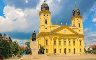 Reformed Great Church in Debrecen with Kossuth Square statues, part of self-guided audio tour.