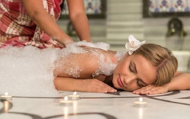 Moroccan Hammam massage with bubbles at historic Marrakesh bathhouse.