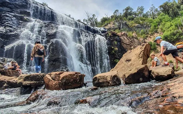 Hikers exploring a waterfall in Grampians National Park during a small-group tour.