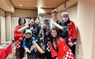 Group participating in traditional mochi pounding, wearing cultural attire, Japan.