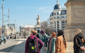 Tourists exploring Bucharest Old Town near historic statues and architecture.