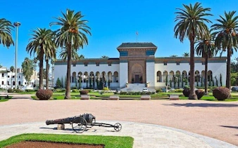 Casablanca city hall with palm trees and historic cannon in foreground.