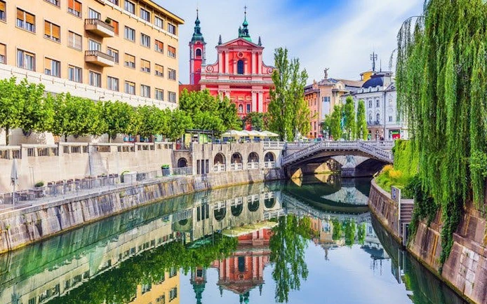 Ljubljana's Triple Bridge and Franciscan Church reflected in the Ljubljanica River.