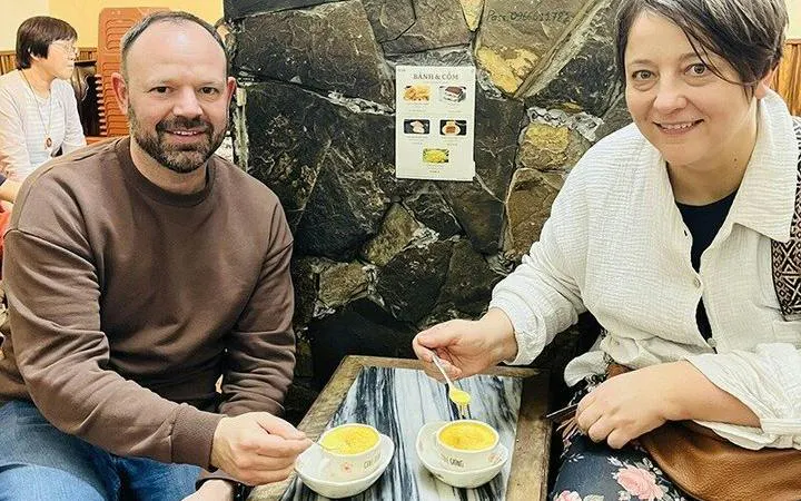 Tourists enjoying egg coffee at a café in Hanoi's Old Quarter during a cyclo tour.
