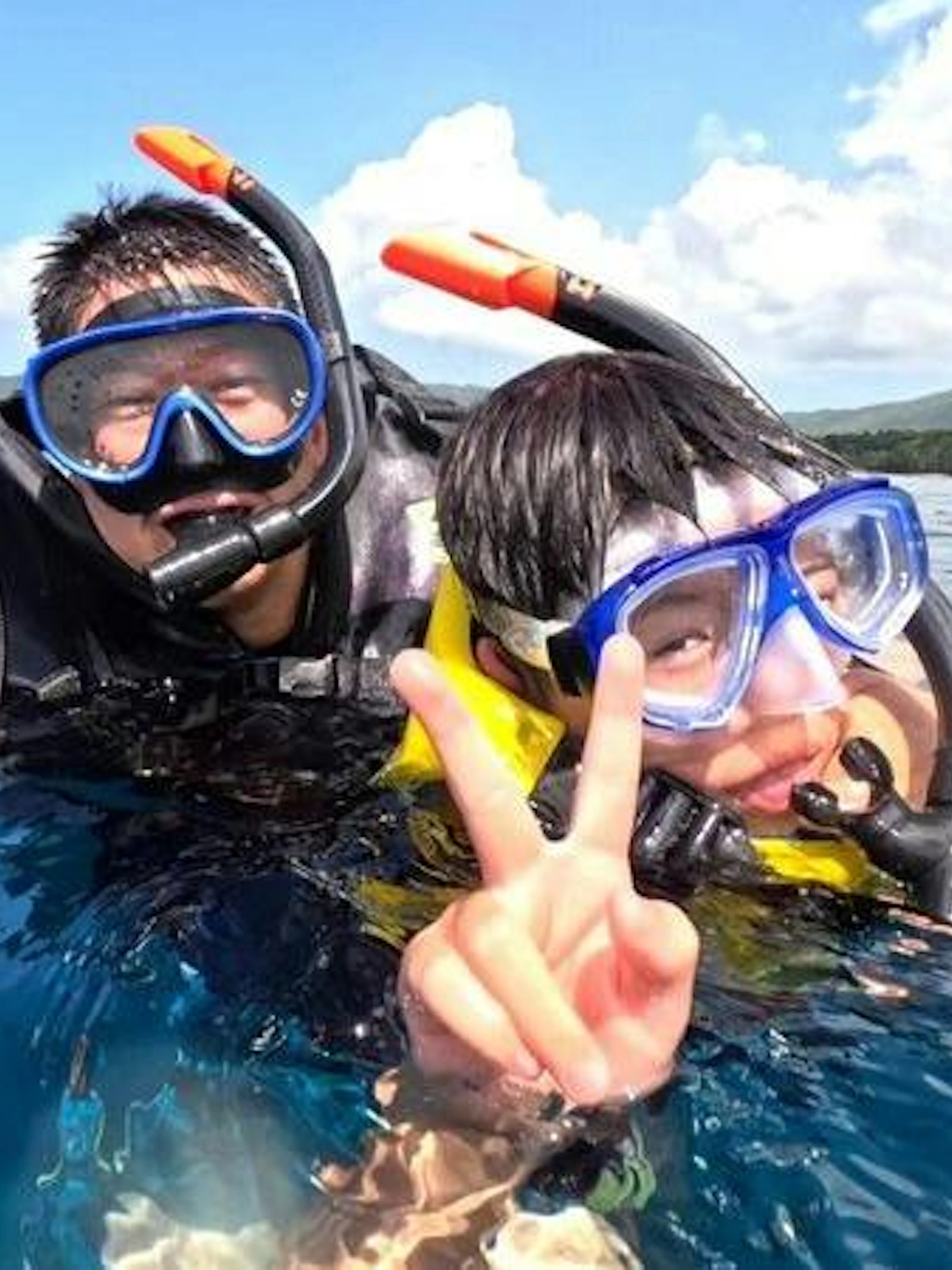Snorkelers enjoying Ishigaki Blue Cave waters, Okinawa, with Taketomi Island in the background.