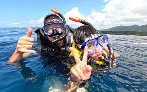Snorkelers enjoying Ishigaki Blue Cave waters, Okinawa, with Taketomi Island in the background.