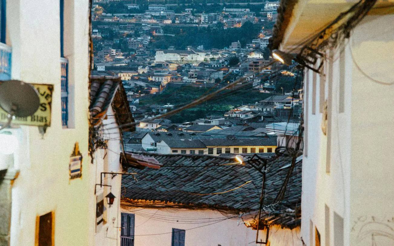 Narrow street in Cusco's San Blas with city view in the background.