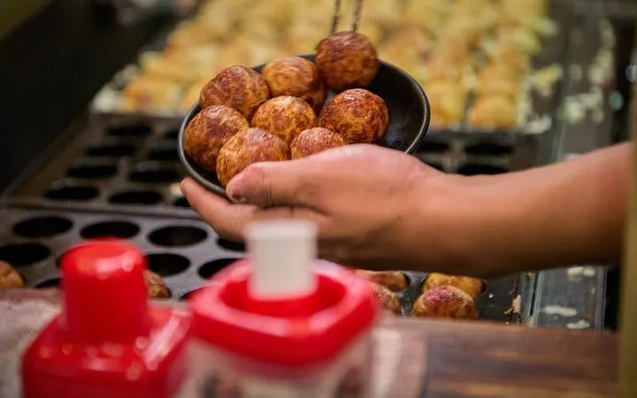 Takoyaki being served at a street food stall in Dotonbori, Osaka.