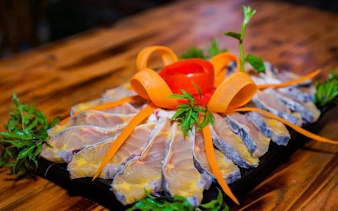Sliced fish with carrot garnish on a platter, part of Sapa hotpot meal experience.