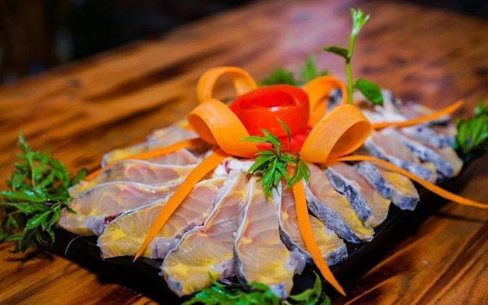 Sliced fish with carrot garnish on a platter, part of Sapa hotpot meal experience.