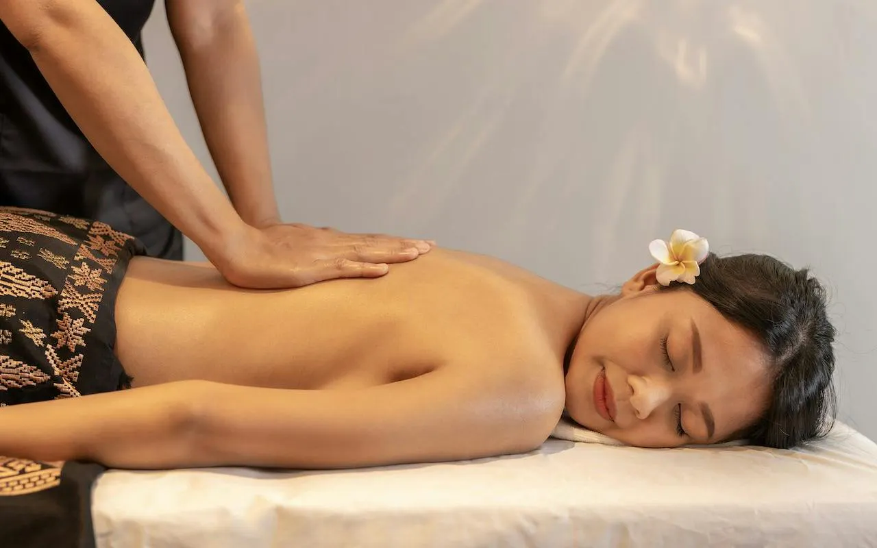 Balinese massage therapy at Ame Spa, Bali, with floral hair accessory.