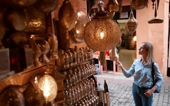 Woman exploring lantern shop in Casablanca market during Marrakesh day trip.