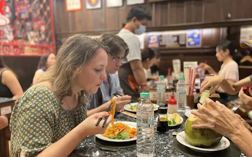Tourists enjoying a meal at a Michelin-recognized restaurant in Bangkok during a food tour.
