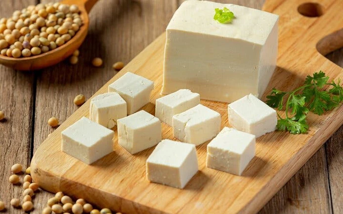 Tofu cubes on a wooden board with soybeans, highlighting Sa Pa cooking class using local ingredients.