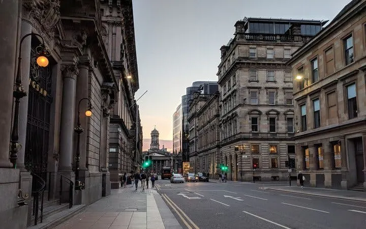 Street view of Glasgow city center at dusk, featuring historic architecture and pedestrians, part of the Ghosts of Glasgow tour.