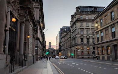 Street view of Glasgow city center at dusk, featuring historic architecture and pedestrians, part of the Ghosts of Glasgow tour.