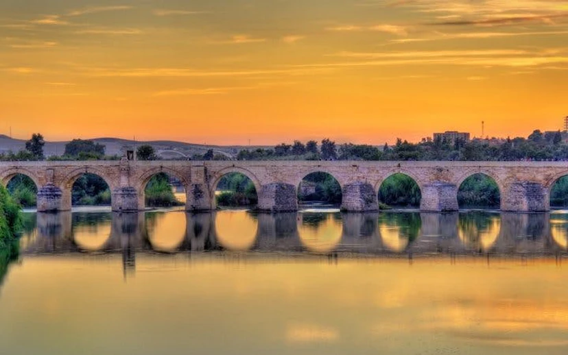 Roman bridge over the Guadalquivir River at sunset in Córdoba, Spain.
