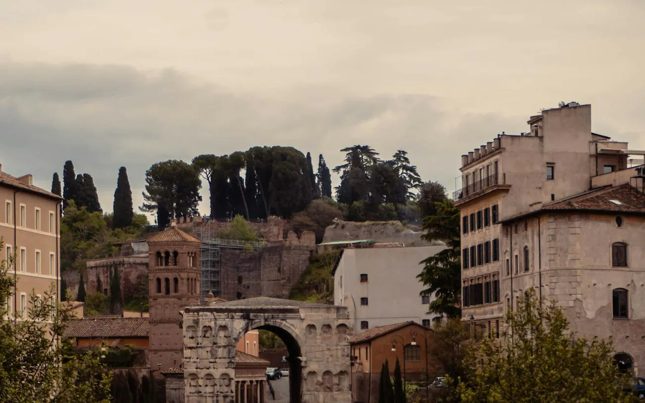 Ancient ruins and buildings near Circus Maximus, Rome, with trees and cloudy sky.