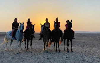 Horseback riders at sunrise in Hurghada desert near Red Sea.