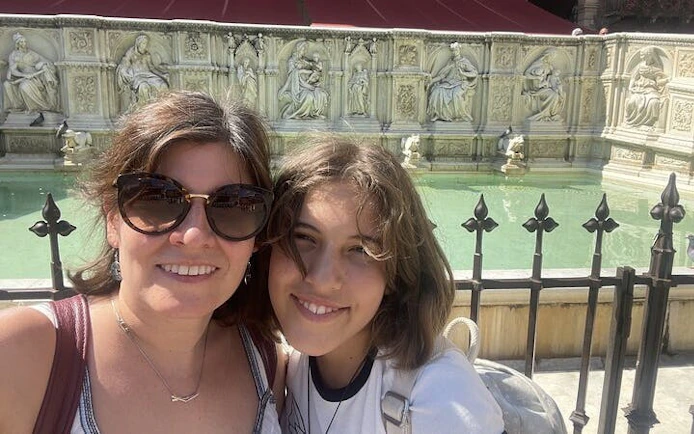 Two people in front of Fonte Gaia fountain in Siena, Italy, part of a self-guided city exploration game.