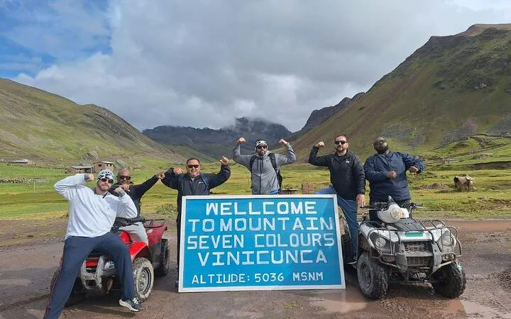 ATV riders at Rainbow Mountain, Vinicunca sign, Cusco tour.