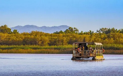 Boat tour on a river in iSimangaliso Wetland Park, with passengers viewing wildlife, near Durban.