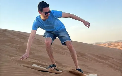 Sandboarding in Dubai desert during evening safari.