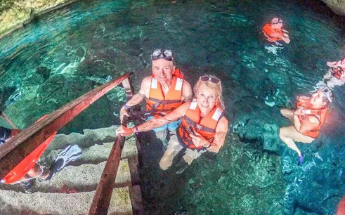 Snorkelers in life vests entering a cenote for a guided tour in Mexico.