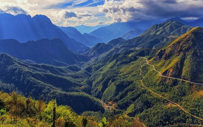 Mountainous landscape in Sa Pa with winding roads and lush greenery.