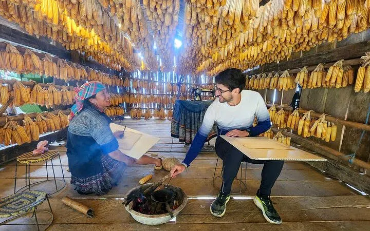 Local woman and tourist in a corn drying house during Sapa and Mu Cang Chai tour.