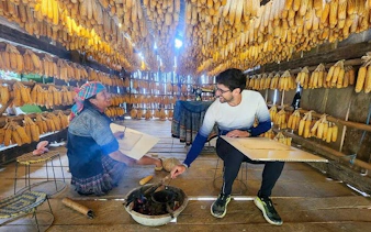 Local woman and tourist in a corn drying house during Sapa and Mu Cang Chai tour.