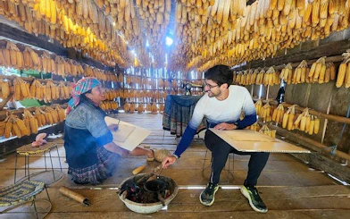 Local woman and tourist in a corn drying house during Sapa and Mu Cang Chai tour.
