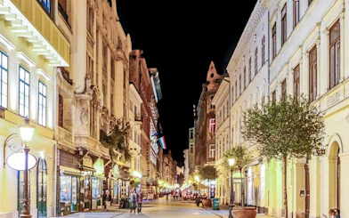 Budapest street at night with historic buildings, part of self-guided city exploration game.